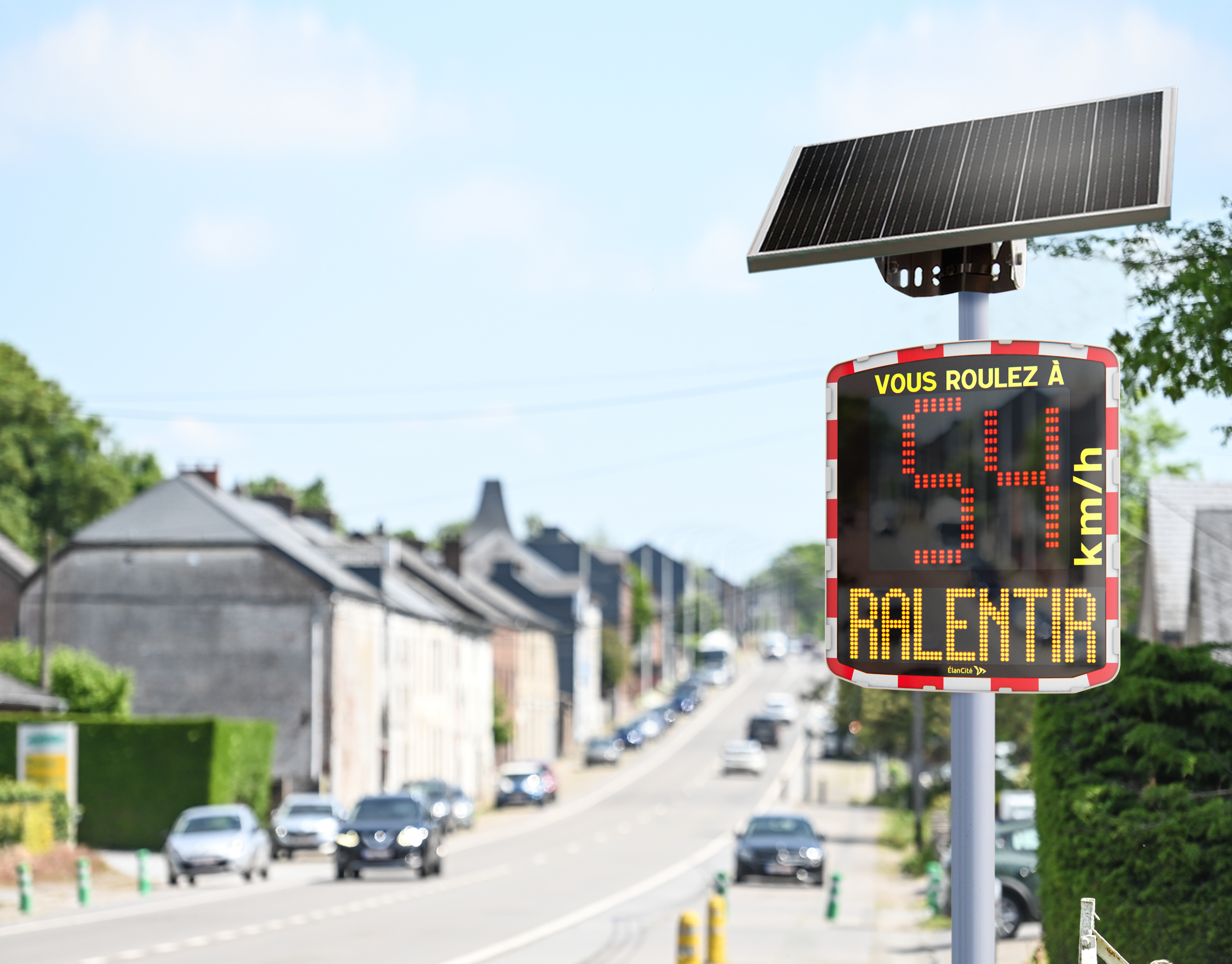 Photomontage d'un radar pédagogique solaire installé aux abords d'une rue communale et qui affiche une allure de vitesse excessive de 54km/h.